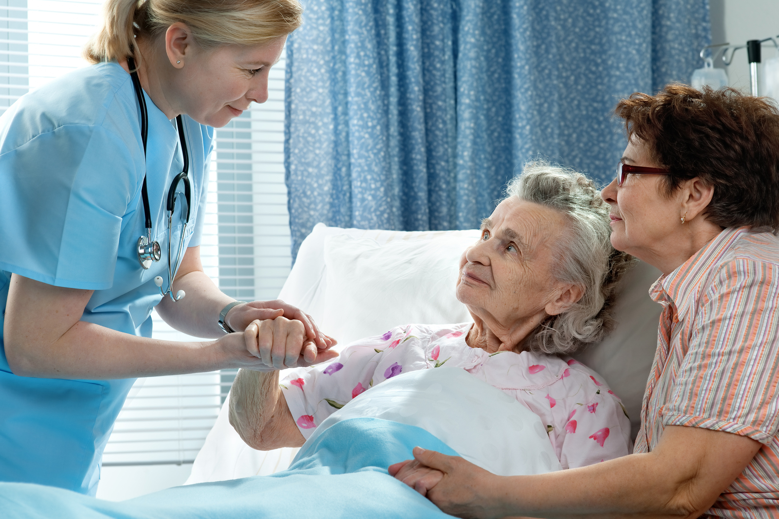 old lady in a bed with daughter and nurse